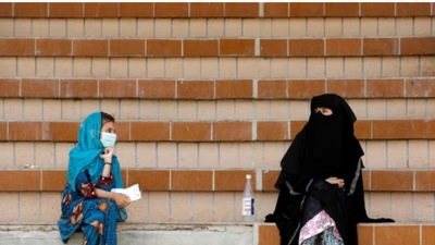 Một phụ nữ và một bé gái Pakistan giữ khoảng cách an toàn khi đang ngồi đợi kết quả xét nghiệm COVID-19 tại một điểm xét nghiệm ở thành phố Karachi, Pakistan. Ảnh: REUTERS