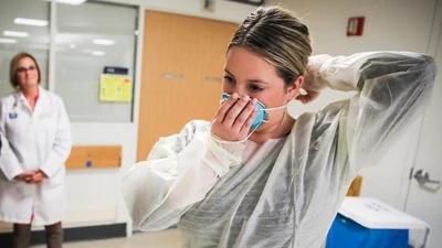 Một bác sĩ hướng dẫn cách đeo khẩu trang đúng cách tại Bệnh viện Massachusetts (Boston) ngày 27-2. Ảnh: REUTERS