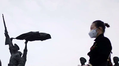 Một người phụ nữ đi ngang qua Tượng đài Cách mạng Tân Hợi ở Vũ Hán hôm 6-4. Ảnh: REUTERS