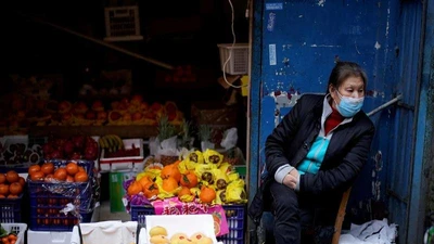 Một phụ nữ đeo khẩu trang ngồi cạnh quầy trái cây tại khu chợ dân cư sau khi lệnh phong tỏa được dỡ bỏ ở Vũ Hán, Trung Quốc ngày 11-4-2020.