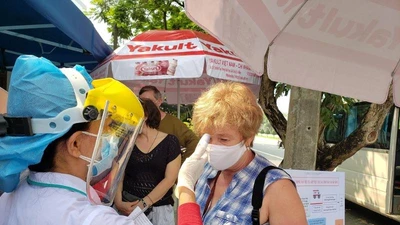 Nhân viên y tế đo thân nhiệt cho một du khách nước ngoài tại điểm chốt ra vào thành phố Đà Nẵng. Ảnh: T.AN 