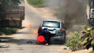 Xe hơi bốc cháy sau khi chạy qua rơm phơi trên đường