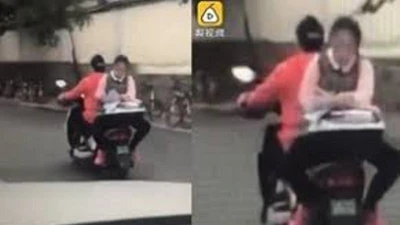 Clip: Nữ sinh ngồi ngược sau xe máy làm bài tập