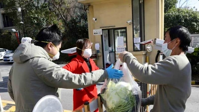 Người dân lấy rau họ mua tại cổng một khu dân cư ở Vũ Hán. 