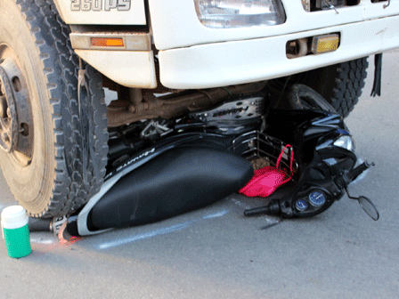 Chiếc xe máy nằm gọn dưới bánh xe tải nhưng chủ nhân may mắn thoát chết. Nhập mô tả cho ảnh