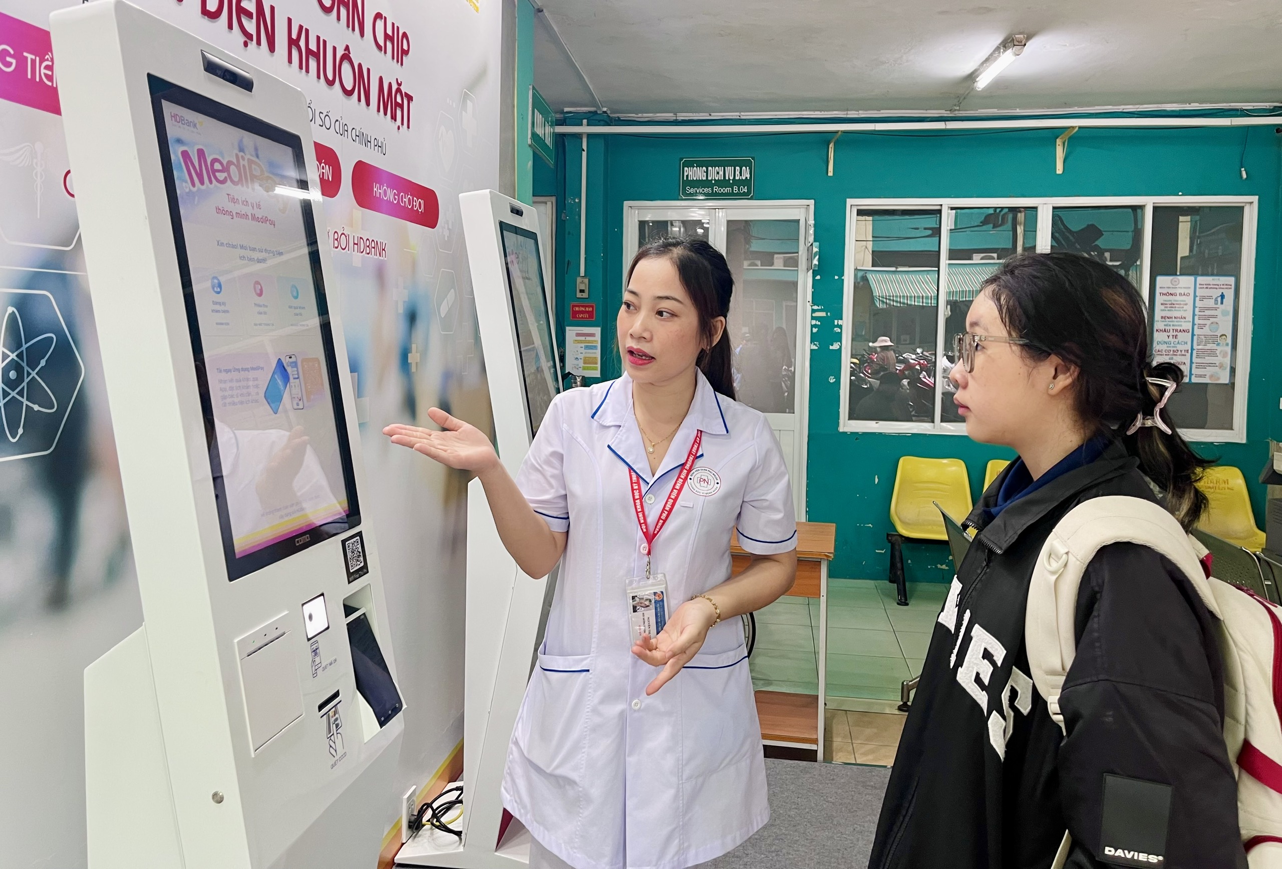Điều dưỡng Nguyễn Thị Thu hướng dẫn bệnh nhân đăng ký khám bệnh bằng ki-ốt thông minh tại BV quận Phú Nhuận. Ảnh: THẢO PHƯƠNG