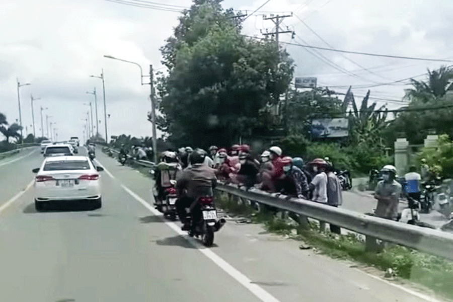 Người dân hiếu kỳ tập trung tại cầu Cái Cấm (xã Thanh Tân, huyện Mỏ Cày Bắc, tỉnh Bến Tre) theo dõi việc khám xét nơi ở của 1 đối tượng có liên quan