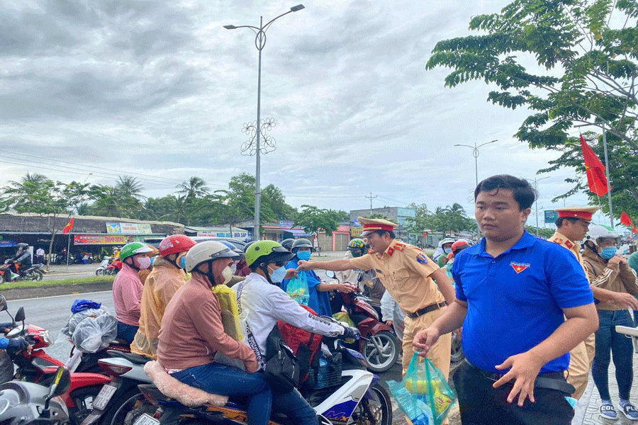 Lực lượng CSGT Công an tỉnh Bến Tre hỗ trợ nước suối, bánh và áo mưa cho người dân trên đường trở lại TP HCM sau kỳ nghỉ lễ 2-9. Ảnh:CSGT