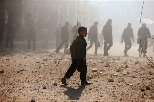  Một cậu bé đi gần một khu vực bị tàn phá bởi trận pháo kích của lực lượng trung thành với Tổng thống Syria Bashar Assad tại Duma, Damascus hôm 22-12. Ảnh: Reuters