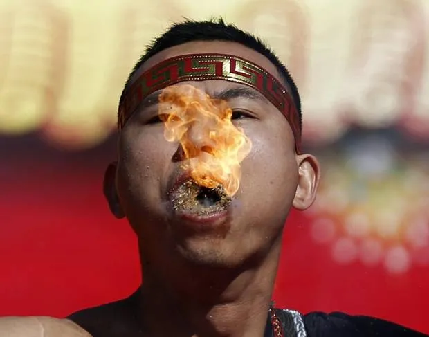 A man holds burning dry grass in his mouth while spitting a flame as he performs a feat of his strength during the opening of the temple fair for the Chinese New Year celebrations at Ditan Park, also known as the Temple of Earth, in Beijing January 30, 2014. (KIM KYUNG-HOON/REUTERS)