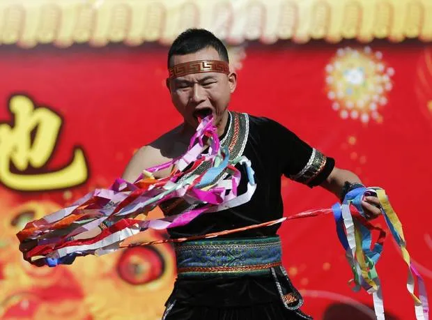 A man pulls ribbons from his mouth as he performs a feat of his strength during the opening of the temple fair for Chinese New Year celebrations at Ditan Park, also known as the Temple of Earth, in Beijing January 30, 2014. (KIM KYUNG-HOON/REUTERS)