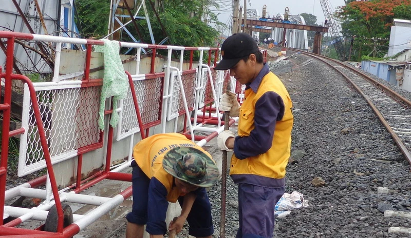 Công nhân hoàn thiện hệ thống thoát nước, gác chắn trên đường Bùi Hữu Nghĩa, thành phố Biên Hòa ở bờ Nam cầu Ghềnh mới để phục vụ cho tàu chạy thử từ ga Dĩ An ra trong chiều nay.