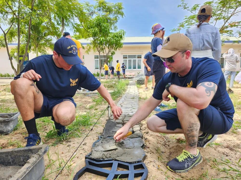 Các thủy thủ trộn bê tông, đắp khuôn làm lối đi cho các bạn nhỏ. Ảnh: TẤN VIỆT