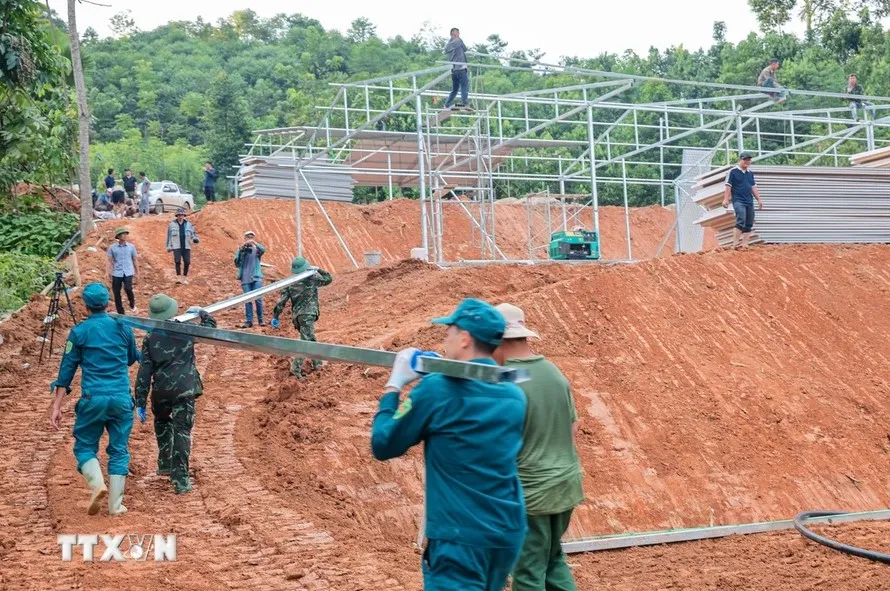 Lực lượng chức năng tập trung, gấp rút triển khai xây dựng khu nhà tạm để chuẩn bị đón người dân Làng Nủ đến ở. Ảnh: TTXVN khu nhà tạm 1.jpg