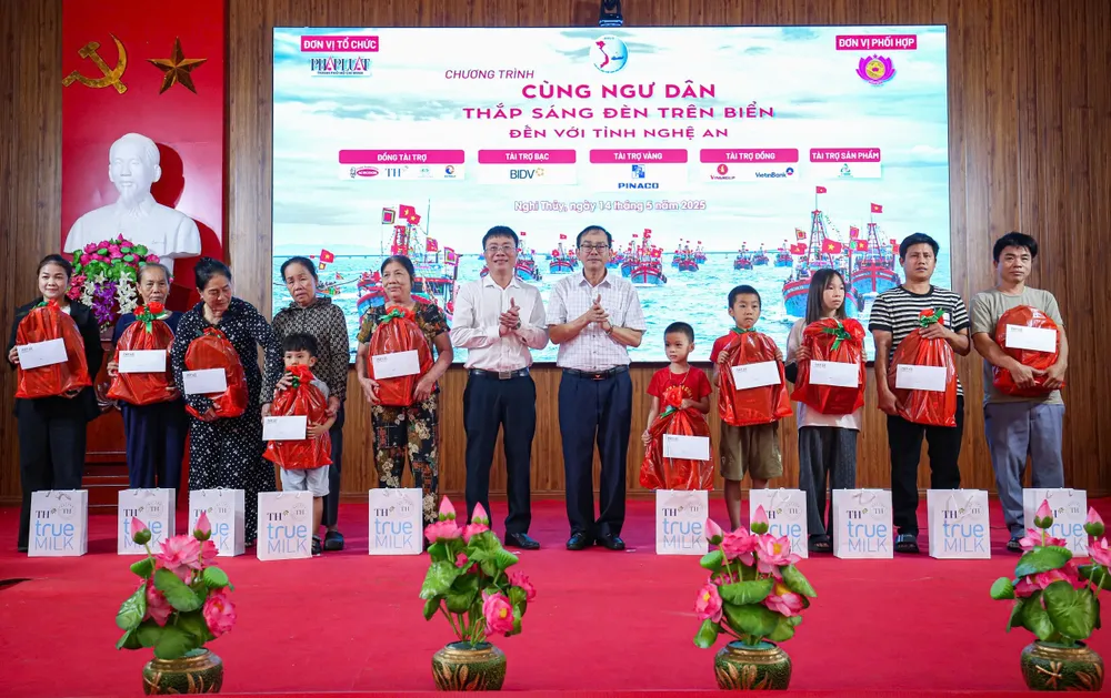 Ông Hoàng Đình Kiên, Phó giám đốc ngân hàng BIDV, chi nhánh Nghệ An (bên trái) và ông Trần Quang Lâm, Phó Chủ tịch UBND TP Vinh, trao quà cho học sinh là con em của các gia đình ngư dân vượt khó, học giỏi. cùng ngư dân 10.jpg