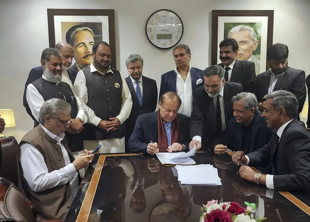 Cựu Thủ tướng Pakistan Nawaz Sharif (ngồi giữa) ký vào một tài liệu khi ông vừa trở về nước hôm 21-10. Ảnh: image.jpg