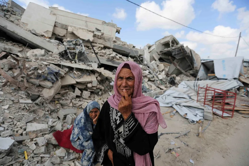 Người dân Gaza đứng trước đống đổ nát tại TP Khan Younis (miền nam Gaza). Ảnh: REUTERS cuộc chiến ở Gaza.jpg