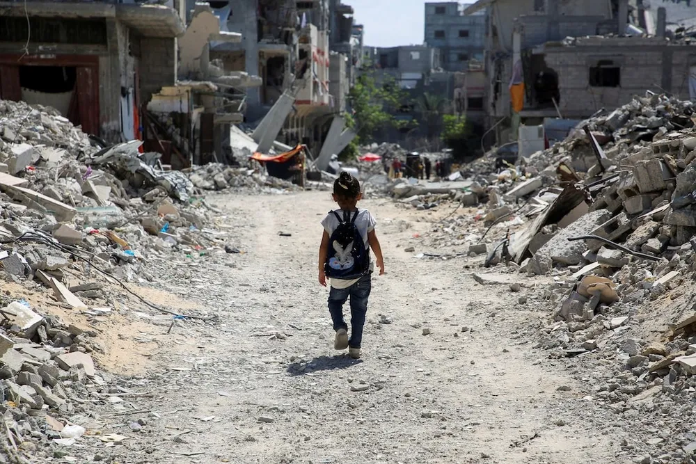 Trẻ em đi qua đống đổ nát hai bên đường ở TP Khan Younis (phía nam Gaza) hôm 4-9. Ảnh: REUTERS Xung đột Israel-Hamas .jpg