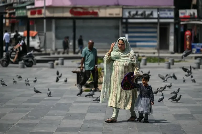 Mẹ và con gái đi bộ qua một khu chợ ở Srinagar, thuộc vùng Kashmir do Ấn Độ quản lý, vào sáng 11-5. Ảnh: AFP Untitled.jpg