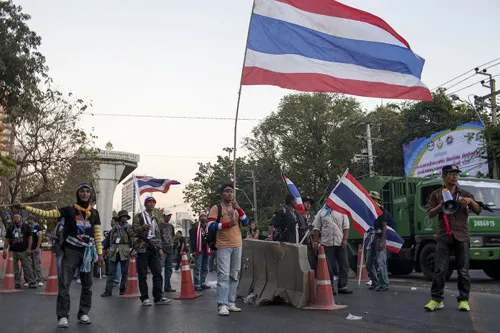 [Caption]Thai anti-government protesters hold national flags as they start massing at one of their designated sites in a move to 'shut down' Bangkok on January 12,