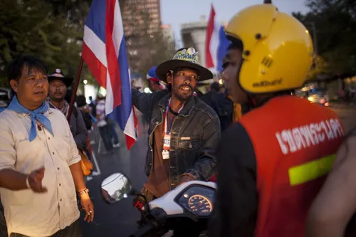 [Caption]Thai anti-government protesters prevent a motorcyclist from driving ahead as they start massing at one of their designated sites in a move to 'shut down' Bangkok on January 12, 2014