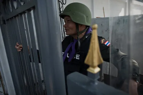 [Caption]A Thai police officer secures a gate outside the Government house in Bangkok on January 12, 2014.