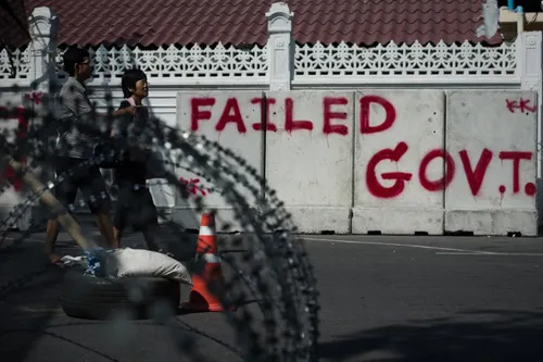 [Caption]Thai anti-government protesters walk outside the Government house in Bangkok on January 12, 2014