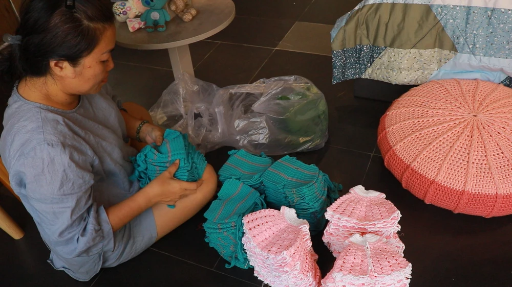 Chị Linh sắp xếp lại những chiếc áo quần búp bê vừa nhận được từ những người thợ lớn tuổi. Ảnh: VT