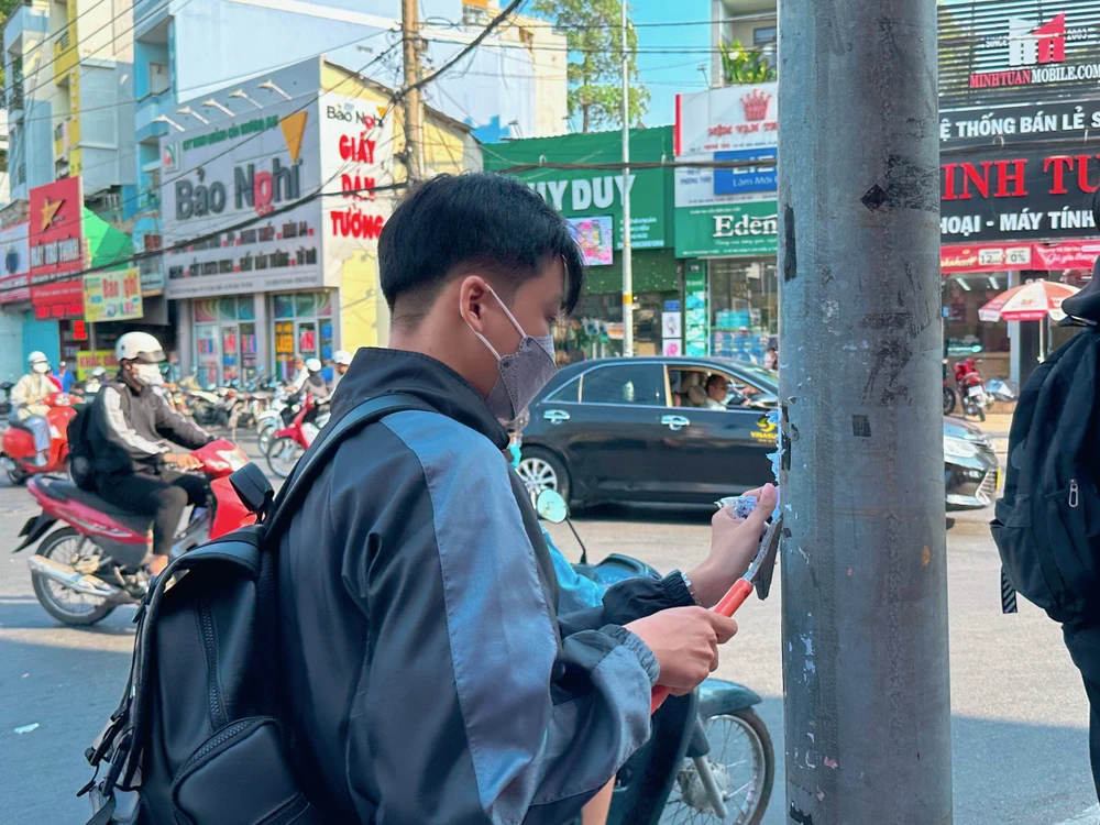 Xé bỏ những quảng cáo được dán trên các trụ điện.