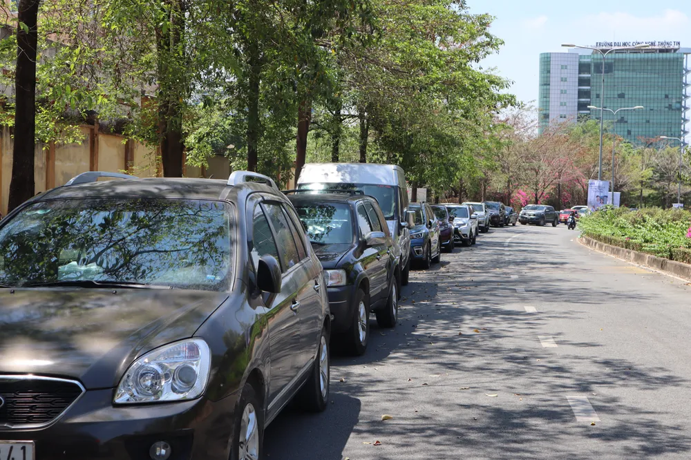 Dọc con đường dẫn vào trường Đại học Công nghệ thông tin và trường Đại học Khoa học xã hội và Nhân văn tập trung nhiều ô tô ngoại tỉnh của các phụ huynh đưa đón con đi thi.