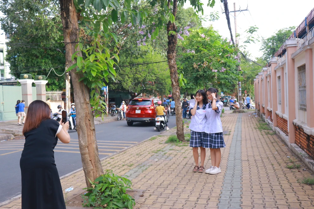 Phụ huynh chụp ảnh lưu niệm cho Bảo Châu và bạn thân tại điểm thi trường THPT Nguyễn Hữu Huân. Ảnh: VÕ THƠ