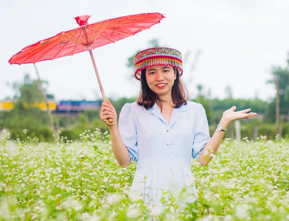 Thạc sĩ Triệu Thy Hòa, giảng viên khoa Khoa học tự nhiên và Kỹ thuật, trường Đại học Quảng Nam bên cạnh vườn hoa Tam giác mạch. Ảnh: Quang Đoàn tam giác mạch