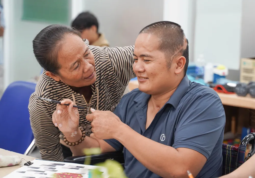 Con trai bà Nga khó giao tiếp, khó cử động vì di chứng chấn thương sọ não để lại do tai nạn cách đây 3 năm. Sau thời gian gắn bó với hội hoạ kết hợp cùng việc điều trị, con trai bà đã nỗ lực giao tiếp, không còn rụt rè, mặc cảm như trước. lop-ve-dac-biet (13).jpg