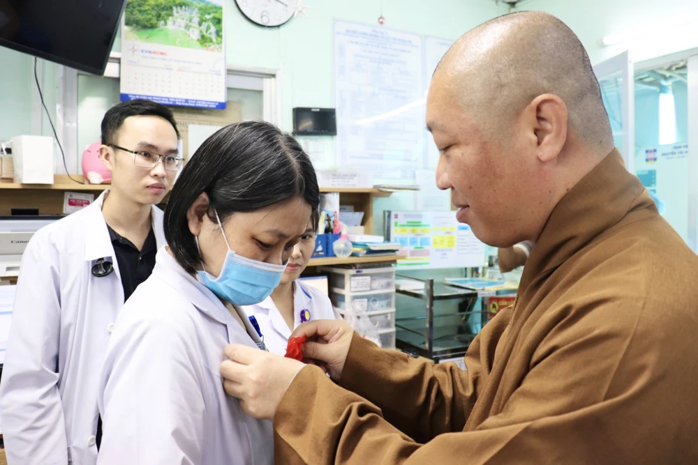 Thượng tọa Thích Thiện Thuận cài bông hồng cho các y bác sĩ. Ảnh: TRẦN MINH