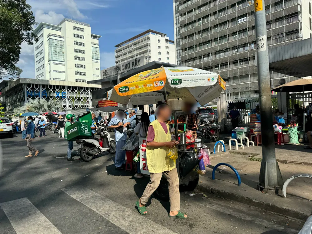 Dù đã được các cơ quan chức năng thực hiện rào chắn xung quanh vỉa hè, thế nhưng tình trạng lấn chiếm vỉa hè mua bán hàng rong trước cổng BV Chợ Rẫy vẫn diễn ra. Ảnh: HUỲNH THƠ bán hàng rong.jpg