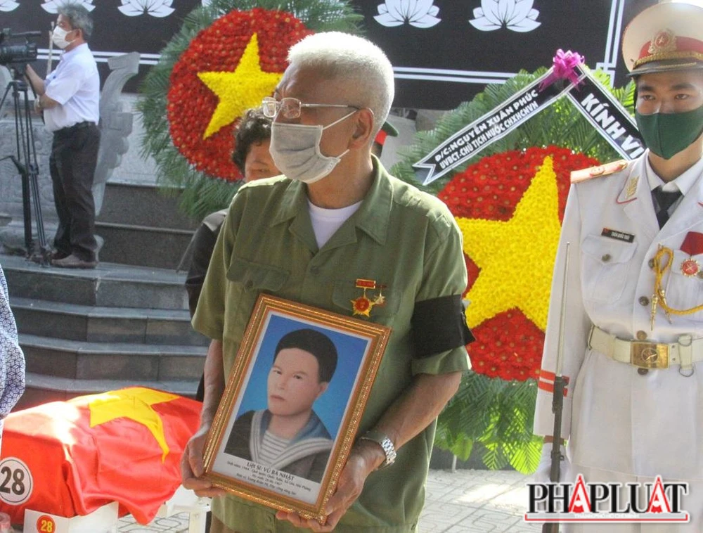 Thân nhân của một trong 28 liệt sĩ ôm di ảnh trong buổi truy điệu và an táng.