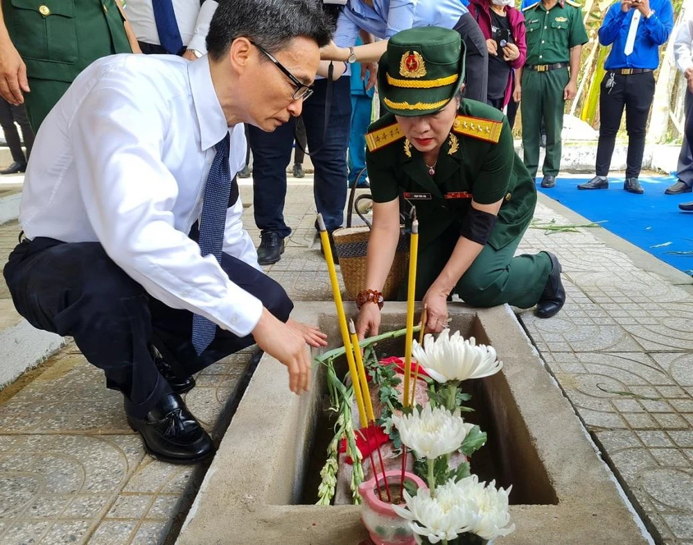 Phó Thủ tướng Vũ Đức Đam thận trọng chỉnh lại hài cốt cho các liệt sĩ.