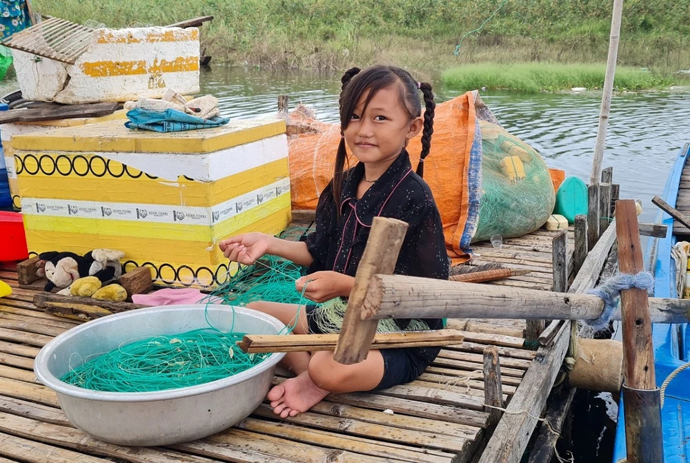 Một bé gái phụ ba ra lưới để chuẩn bị cho buổi tối đánh bắt.