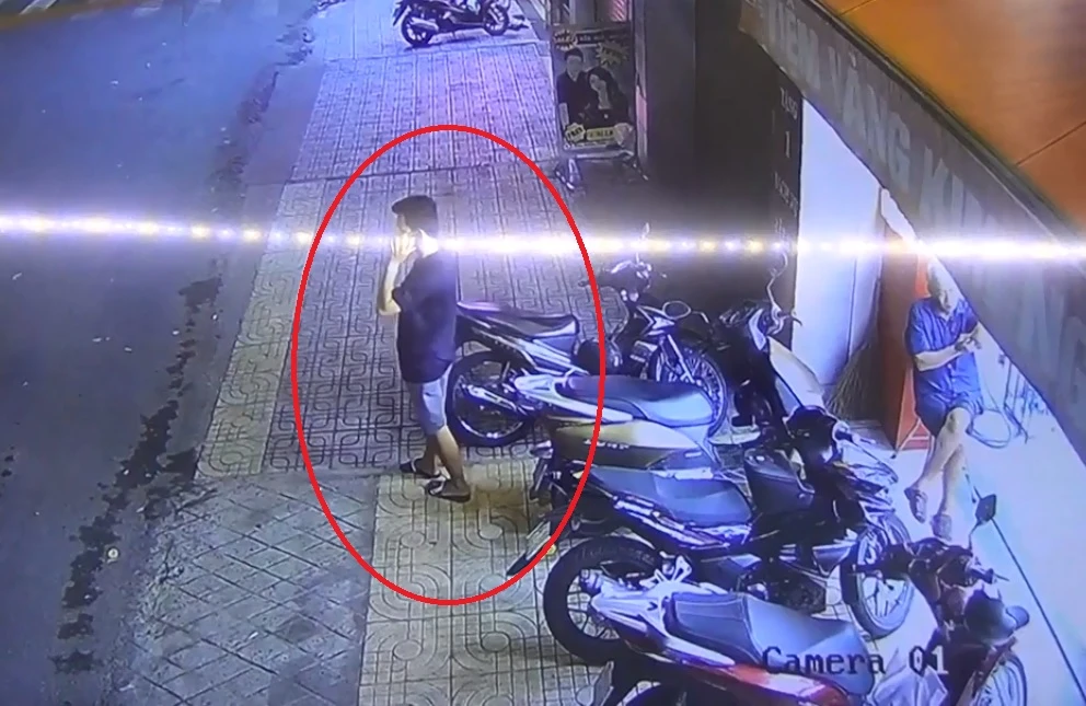 Nghi can ra ngoài cửa tiệm vàng vờ nghe điện thoại để bỏ chạy. Ảnh: Cắt từ camera.