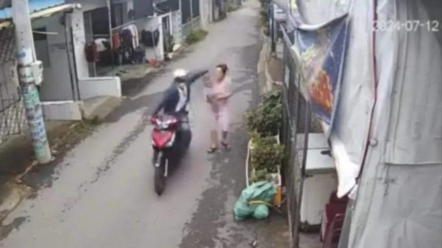 Nghi can Tuấn thực hiện giật dây chuyền vàng của một phụ nữ đang bế con nhỏ. Ảnh: Cắt từ clip Cướp giật dây chuyền .jpg