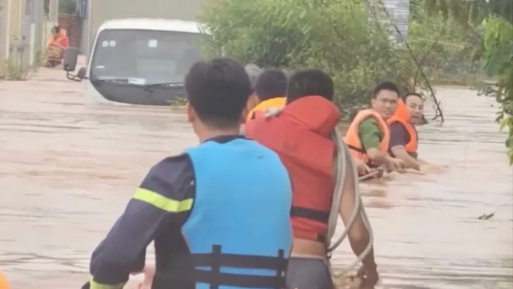 Lực lượng công an đưa những người dân bị mắc kẹt khỏi vùng nước sâu đang chảy xiết. Nước lũ dâng cao 2.jpg