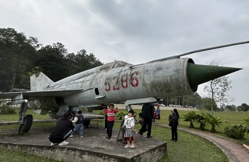 Người dân chụp ảnh lưu niệm tại một chiến đấu cơ trong khu di tích. Ảnh: VŨ LONG