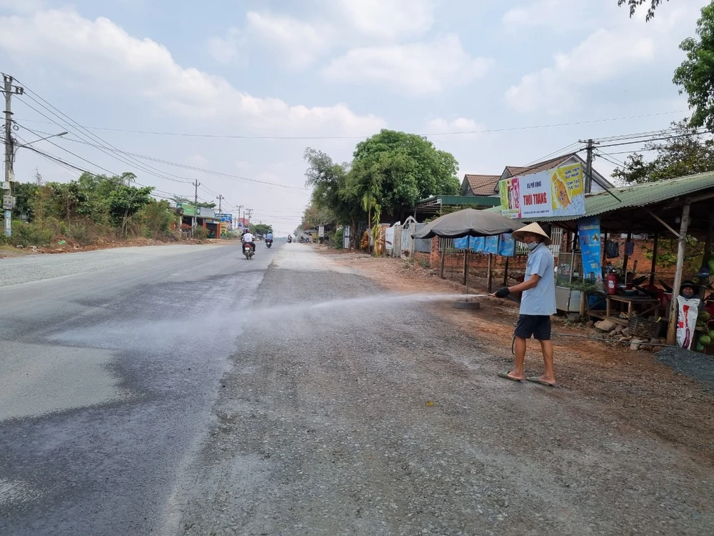 Người dân tưới nước ở công trường đang thi công để hạn chế bụi bẩn. Ảnh: TT z5362828527851_a6e3ac8f4692ed5547c0eeee1c15fb64.jpg