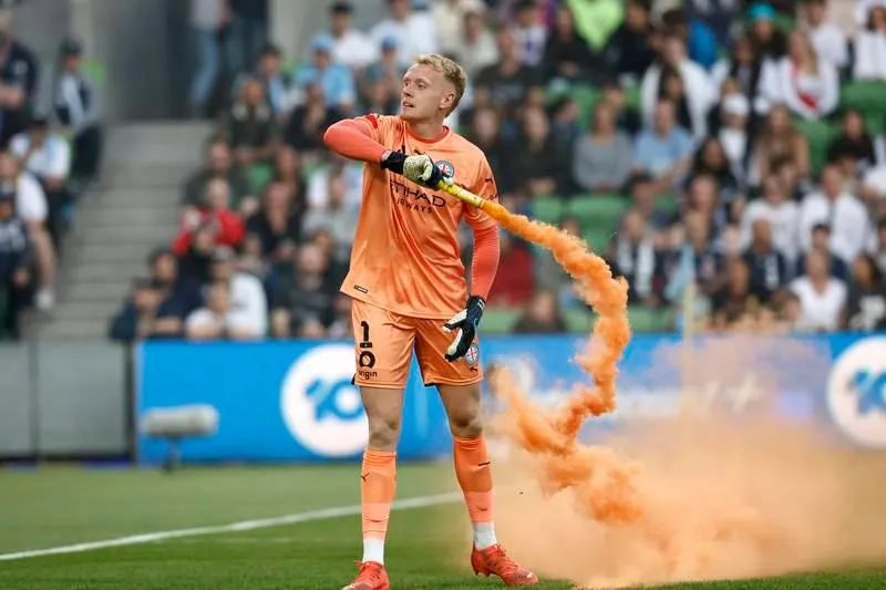 Thủ môn Tom Glover của Melbourne City đã lượm ném quả pháo sáng ra ngoài. Bạo động không phải xuất phát từ tính chất căng thẳng trận derby Melbourne. ... mà do ban tổ chức A-League đưa vòng chung kết của giải đấu này về Sydney ba mùa liên tiếp khiến fan Melbourne cay cú. Họ cáo buộc rằng, ban tổ chức A-League đã ăn tiền bẩn để đưa vòng chung kết A-League về Sydney ba mùa liên tiếp. Vụ lộn xộn này xuất phát từ một fan la lớn phản đối sau đó nhanh chóng lan rộng ra. Fan tràn xuống sân phá rồi đu người lên cả cầu môn.