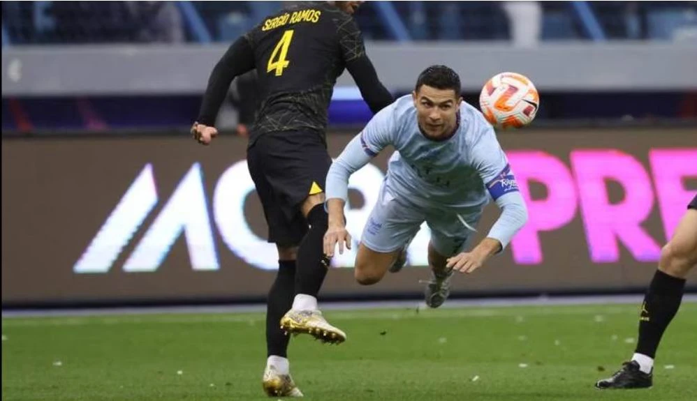 Ronaldo vẫn rất dũng mãnh ở tuổi 37. Messi trong một pha chạm trán với thủ môn Al Owais của Liên quân Al Nassr-Al Hilal. Mbappe và... ông anh Ronaldo. Một trận giao hữu quá nhiều siêu sao nhưng tính đối kháng không cao. Mbappe góp một bàn thắng vào chiến thắng 5-4 của đội khách đến từ thủ đô nước Pháp. Juan Bernat của PSG bị trọng tài người Qatar rút thẻ đỏ. Trợ lý của Liên quân bắt tay Ronaldo. Tổ trọng tài người Qatar điều hành trận đấu, Ronaldo là đội trưởng của Liên quân còn Marquinhos làm đội trưởng PSG. Trận đấu thắng lớn về mặt tài chính.