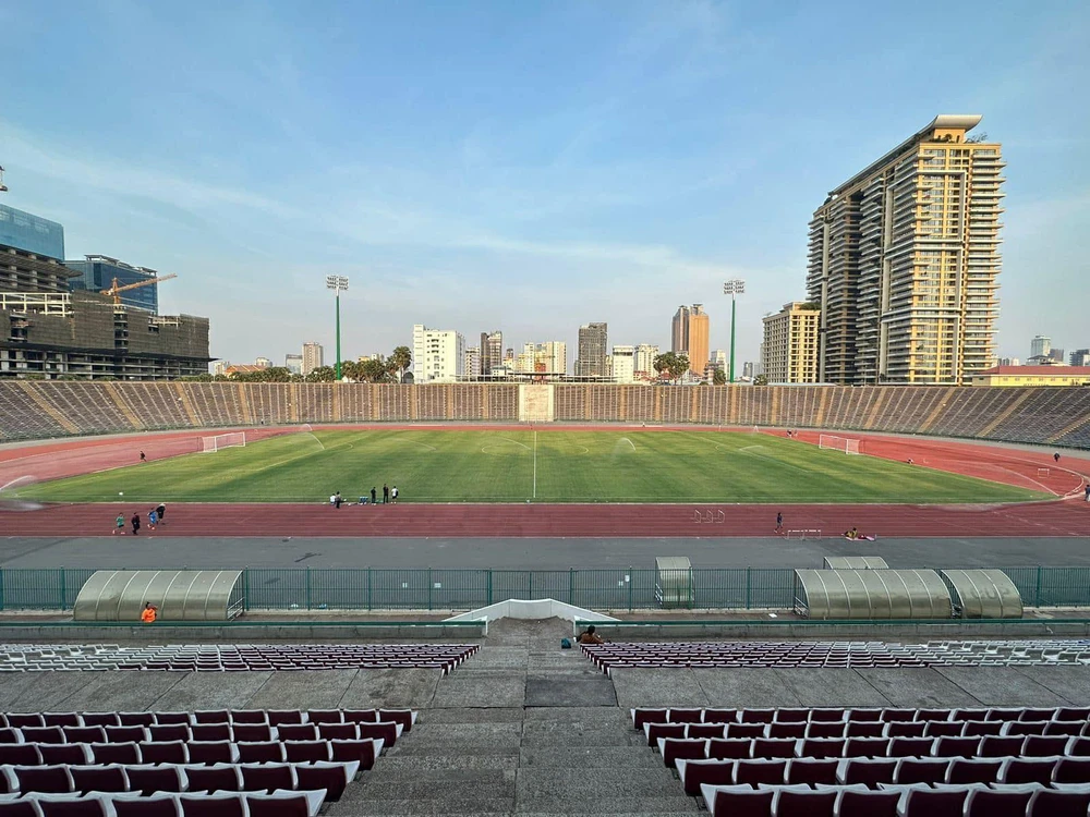 Sân Olympic tọa lạc ngay trung tâm thủ đô Phnom Penh có sức chứa 50 ngàn chỗ ngồi. Sân được xây dựng và hoàn tất năm 1963 khi Campuchia được chỉ định chủ nhà SEA Games năm đó, song do những biến động chính trị trong nước nên SEA Games 1963 bị hủy. Ảnh: CTP Sân vẫn được dùng là sân quốc gia của đội tuyển Campuchia, nhiều thập niên qua, mặt sân phủ cỏ nhân tạo. Ảnh: CTP ...Cho đến trước thềm SEA Games 32 này mặt cỏ chỉ được phủ lên để tổ chức các trận bóng đá nam và nữ SEA Games 32. HLV Honda của U-22 Campuchia...thử độ mềm của sân. Ảnh: CTP "Bóc tem" các ghế ngồi thô sơ bằng nhựa. Ảnh: CTP ...Công nhân dùng búa để bắt đinh gắn chặt ghế vào bê tông. Ảnh: CTP Khi vào bên trong sân Olympic ở Phnom Penh này cảm giác rất giống bên trong sân Cần Thơ. Ảnh: CTP Lắp đặt ghế tạm thời là hạng mục cuối cùng của sân Olympic chờ ngày 29-4 quả bóng môn bóng đá SEA Games 32...lăn. Ảnh: CTP