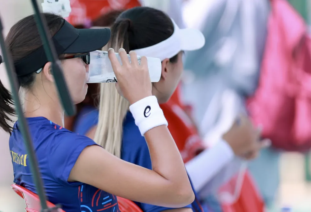 Các tay vợt VN tranh thủ tiếp nước khi tập luyện dưới cái nắng nóng khủng khiếp ở Phnom Penh. Ảnh: ANH PHƯƠNG