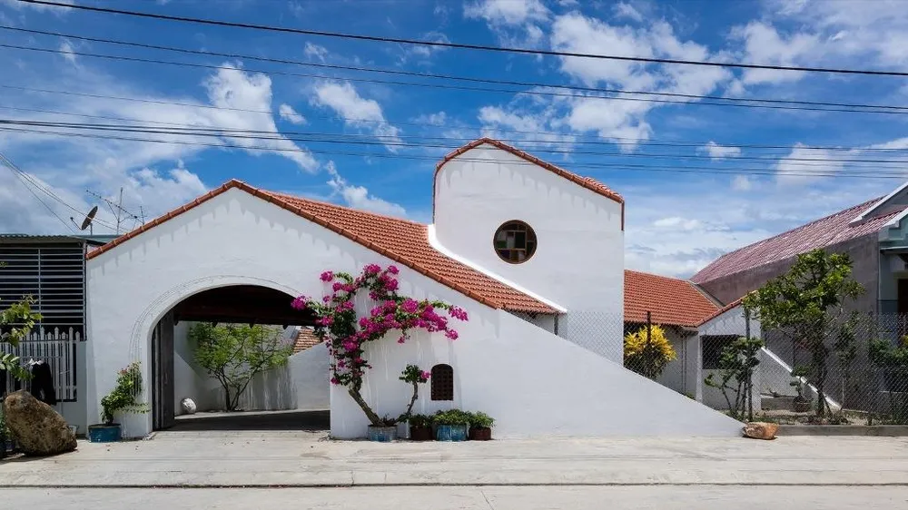 Mặt tiền công trình bởi hai khu vườn hình tam, giác và các vật liệu như tường gạch trắng, dầm gỗ, khe hở và mái nhà.