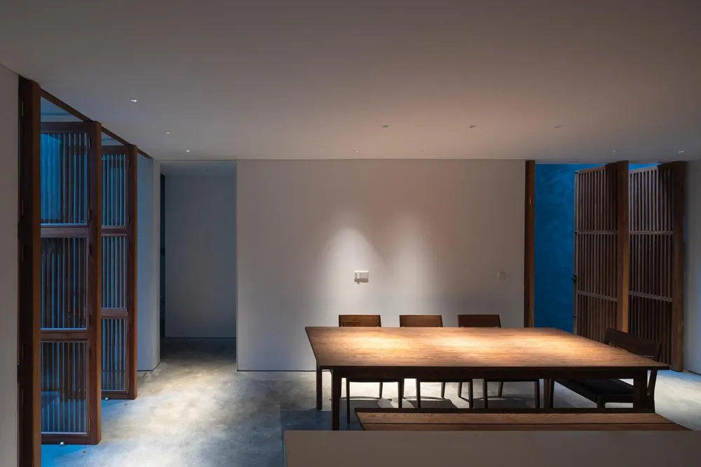 Bàn ăn bằng gỗ bố trí gần khu vực cửa lớn đóng mở linh hoạt dẫn ra bên ngoài sân vườn.