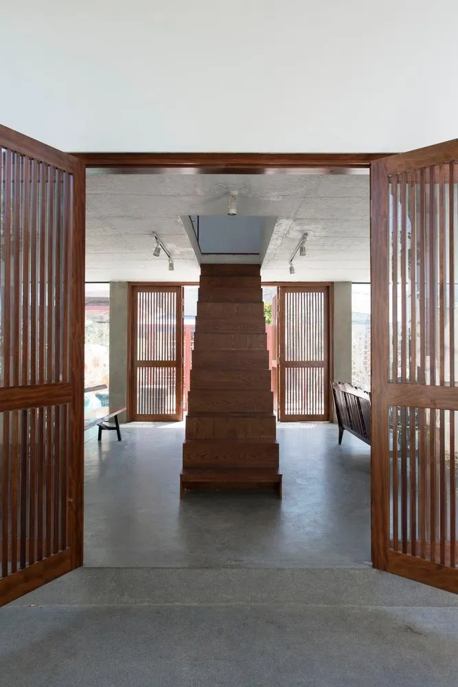 Kiến trúc sư thiết kế cầu thang bằng gỗ ngay lối cửa chính vào nhà.